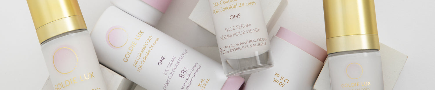 Goldie Lux | 24 Karat Colloidal Gold ONE Collection face serum, eye cream, and face cream bottles with gold caps.