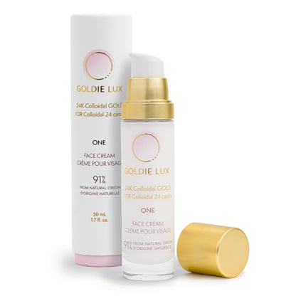 Goldie Lux | 24 Karat Colloidal Gold Face Cream 50 mL. Cap is removed from glass bottle to show pump, and the outer packaging sits behind the bottle.