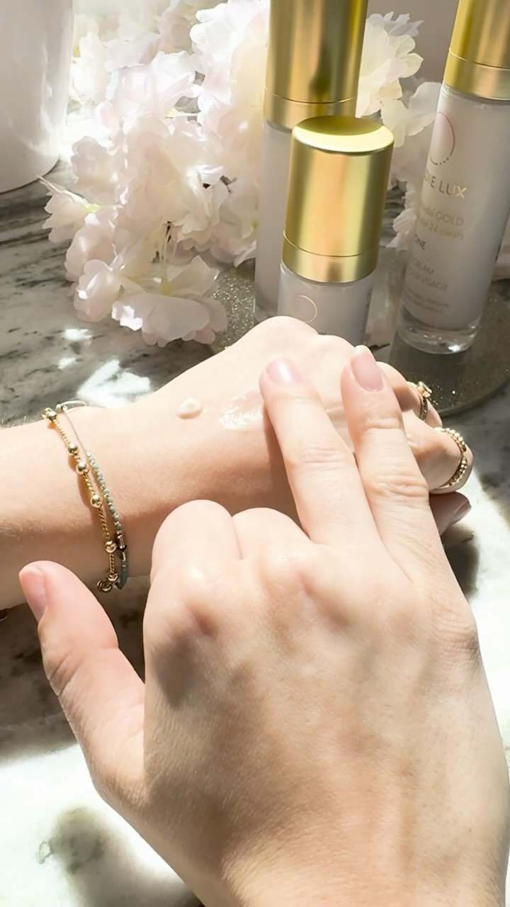 Goldie Lux | 24 Karat Colloidal Gold One Collection face cream, face serum, and eye cream being spread on a woman's hand.